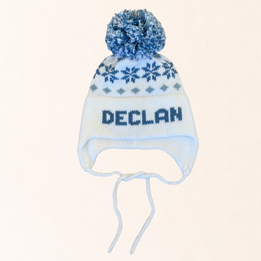 Knitted hat with snowflake pattern and pom-pom on a beige background