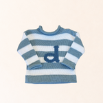 Blue and white striped sweater with a logo on a light beige background