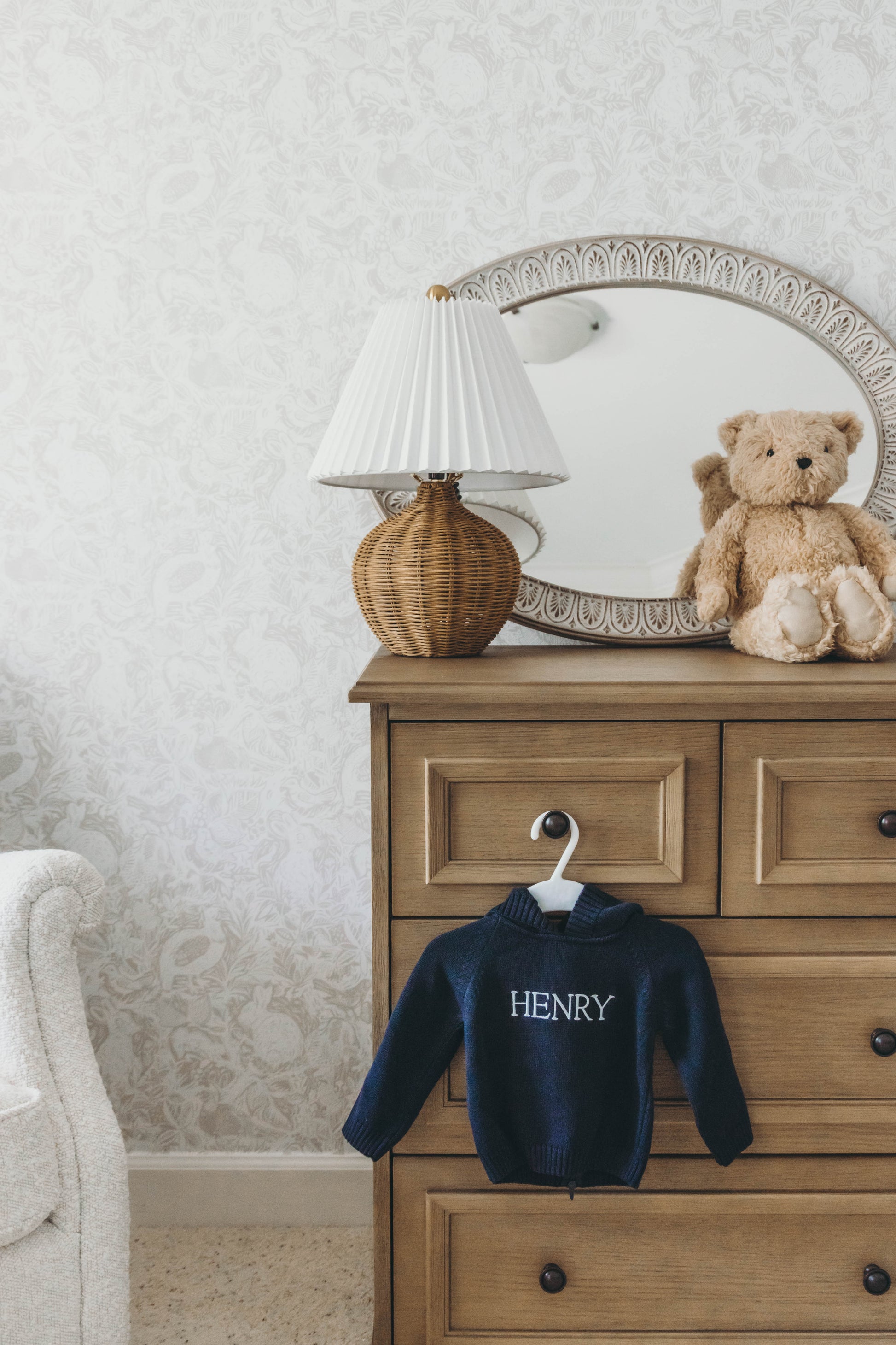 Navy knit sweater for kids personalized with the name "Henry" in white stitching hanging on a dresser drawer