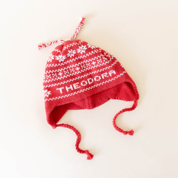 Red knit hat on a neutral background laying flat