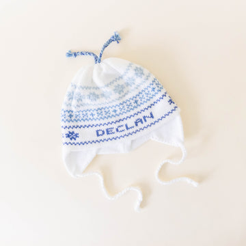 White and blue knit hat personalized with the name "Declan" on a neutral background