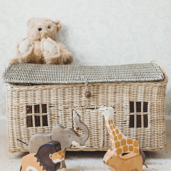 Safari Wooden Animal Set on the floor in front of a wicker toybox