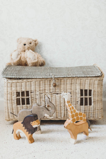 Safari Wooden Animal Set on the floor in front of a wicker toybox