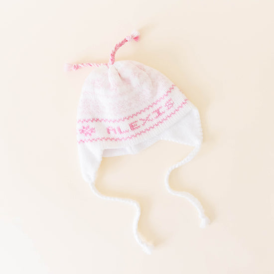 White knit hat with pink stitching personalized with the name "Alexis" on a neutral background