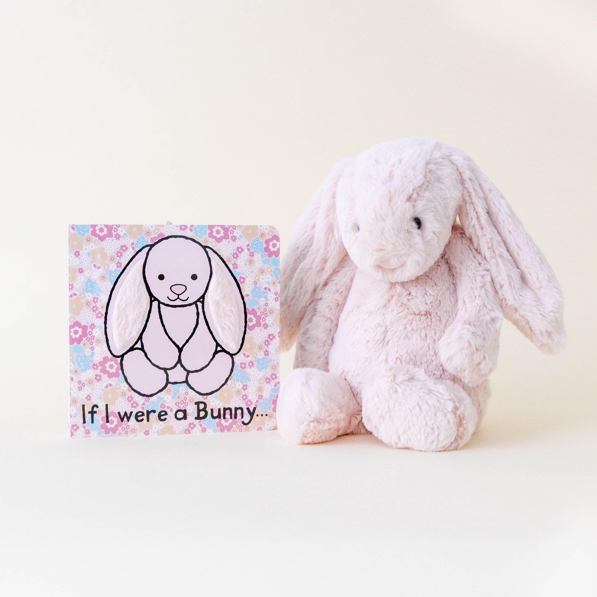 Pink bunny stuffed animal and book titled "if I were a bunny" on a neutral background