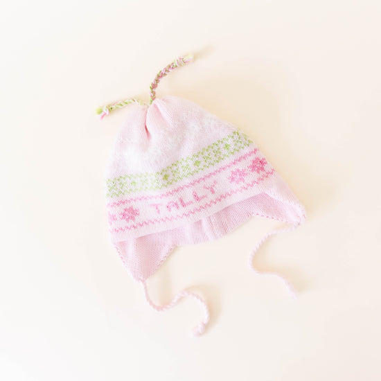 Pink knit hat with pink and green stitching personalized with the name "Tally" on a neutral background