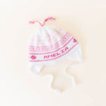 White knit hat with pink stitching personalized with the name 