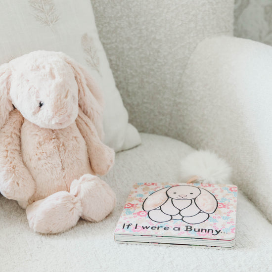 Pink bunny stuffed animal and book titled "if I were a bunny" on a boucle chair