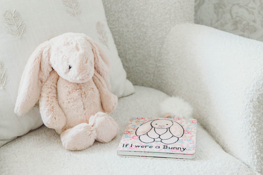 Pink bunny stuffed animal and book titled "if I were a bunny" on a boucle chair