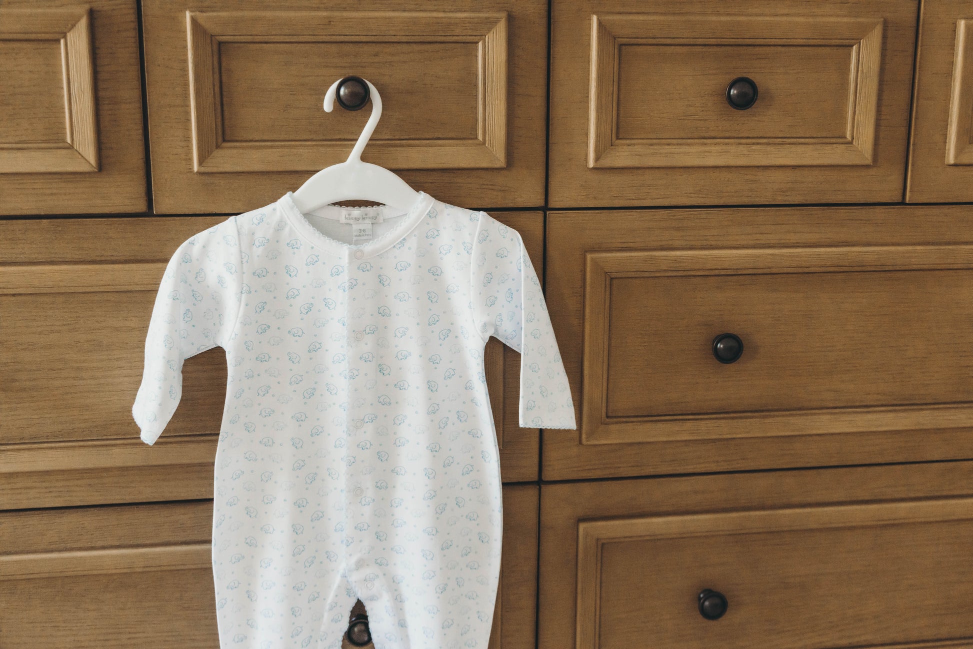 Elephant onesie in blue hanging on a dresser drawer knob closer up